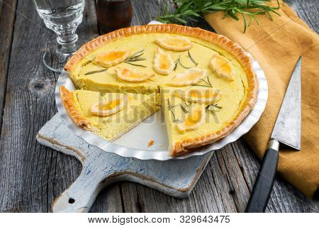 Traditional French Autumn pumpkin tarte offered as closeup in a backing form on an old wooden cutting board 