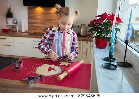Pretty Little Girl With Funny Pigtails Decoraiting Christmas Cookies Of Different Forms In Kitchen