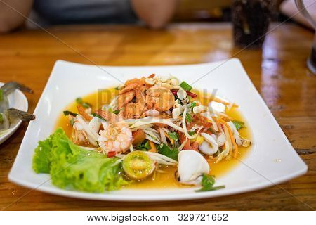 Hot And Spicy Seafood Papaya Salad In White Ceramic Plate On Wooden Table