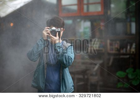 Asian Male Photographer Holding Film Camera With Fog
