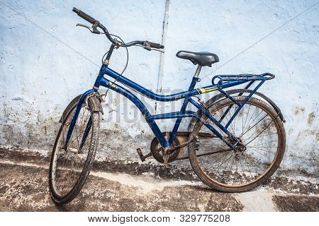 Blue Colored Old-styled Bicycle Isolated Against A Blue Rough Wall.