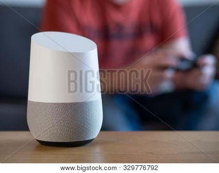 Smart Home Voice Activated Speaker In Lounge With Gamer In Background