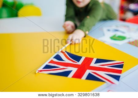 Young Girl Is Holding Union Jack Flag. British Flag On The Front View. Blurred Background. Closeup.