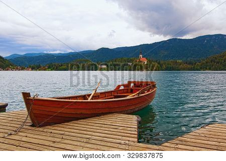 Picturesque Nature Landscape With One Wooden Boat Moored On Bled Lake (blejsko Jezero). Famous Touri