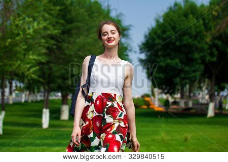 Close up, Young beautiful brunette girl in summer dress walks in the park