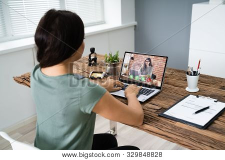 Young Woman Videoconferencing With Colleague On Computer At Desk