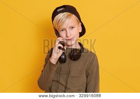 Portrait Of Serious Little Boy With Blond Hair And Green Sweater Talking With Her Friend Or Mother V