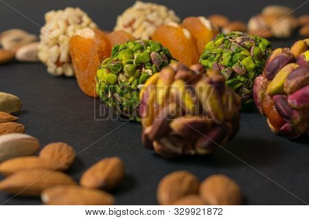 Green Pistachio Confectionery Behind Brown Candies. Healthy No Sugar Food. Scattered Pistachio And A