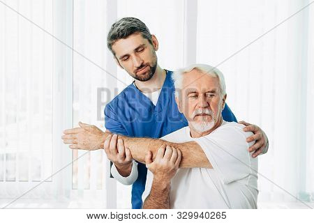 Senior Patient While Exercise Treatment With His Physiotherapist. Rehab At Medical Center