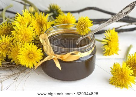 Jar Of Homemade Delicious Dandelion Jam On A Light Wooden Table With Yellow Dandelions. Flower Dande