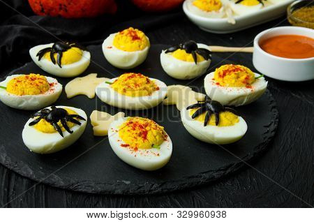 Halloween Stuffed Eggs With Cheese And Mustard On A Black Stone.