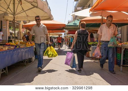 Lamia Greece - July 26 2019; People With Their Purchases Walk Between City Street Market  Produce Ve