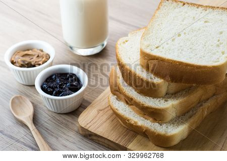 Wooden Board With Breakfast Bread Slices With Milk On The Wooden Table. Black Currant Jam And Peanut