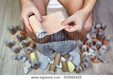 A Man With An Upset Stomach Due To Dysentery Or Dysbiosis Is Sitting On The Toilet In The Wc, With A