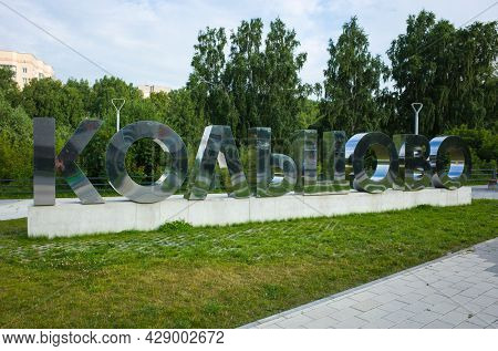 Science city Koltsovo, Novosibirsk, Russia - 24 July, 2021: Word in Russian Koltsovo large silver metal mirror letters on background of green forest in Work settlement of Koltsovo