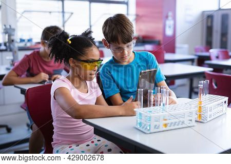 African american girl and caucasian boy using digital tablet in science class at elementary school. school and education concept