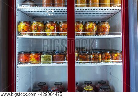 A Refrigerated Display Case With Cans Of Canned Home Products, A Refrigerator With Canned Fruits And