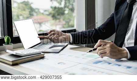 Man Pointing At Laptop Screen And Documents Lying On The Table, Business Man In Black Suit Is Sittin