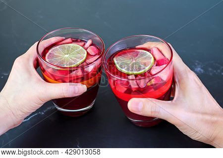 Woman And Man's Hand Holding Glass Of Red Wine Sangria On Black Table