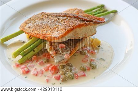 Plate Of Pan Seared Sea Bass With Tomato Caper Mustard Cream Sauce