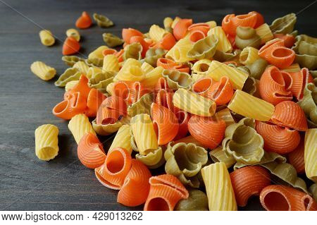 Heap Of Uncooked Dried Vegeroni Pasta On Black Wooden Background