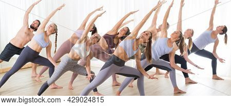 Group Of Young Sporty Attractive People In Yoga Studio, Practicing Yoga Lesson With Instructor, Stre