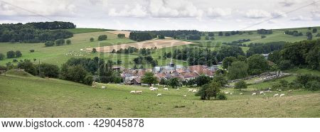 Cloudy Sky Over Summer Countryside Landscape With Green Meadows And Village With Cattle In French Ar