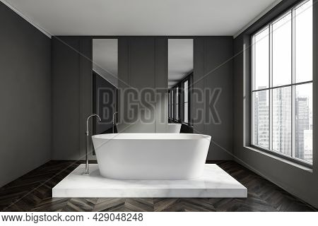 Grey Bathroom Interior With Dark Parquet Flooring And A White Oval Bathtub On A Marble Platform. Tre