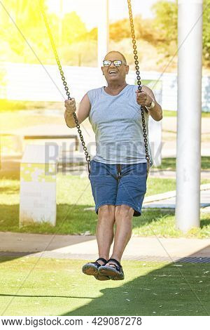 Active Happy Senior Man On Swing. Happy Elderly Positive Pensioner On Swing In Sun Light. Carefree R