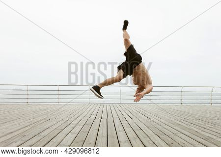 Muscular Man Doing A Head Jump Upside Down Without Touching His Hands To The Floor On The Beach