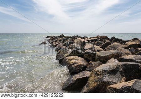 Jetty Of Rock Boulders Extending Out Into The Ocean In Narragansett Rhode Island With Swerling Water