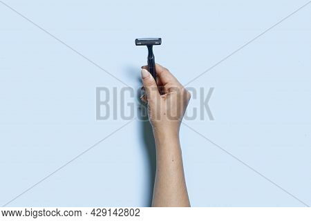 A Person Hand Holds A Multiple Use Shaving Razor On Blue Background. View From Above