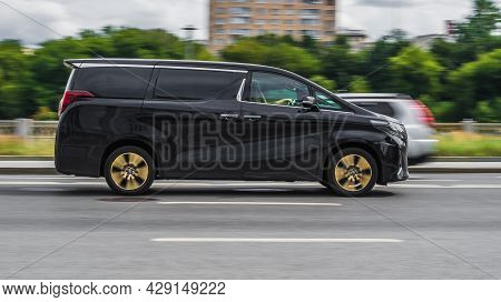 Fast Moving Toyota Alphard On The City Road. Black Mpv Rides On Street. High Class Minivan In Fast M