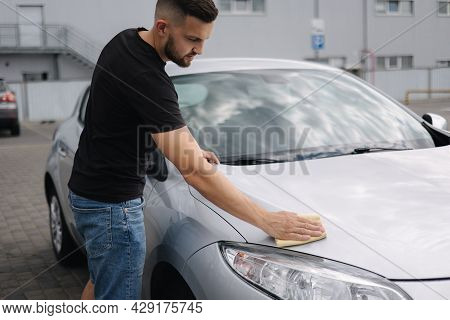 Hand Of Man Wipes Headlight Of His Car Using Rug. Self-service Car Wash. Outdoor