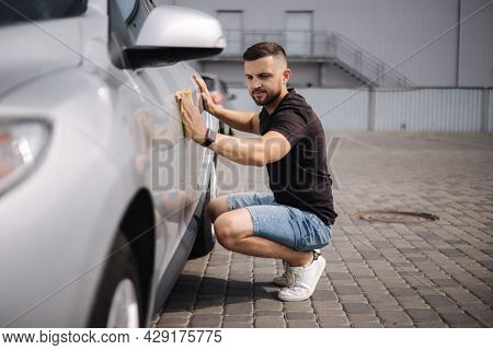 Handsome Man Wipes A Car With A Rag In A Showroom At A Self-service Car Wash. Gray Car
