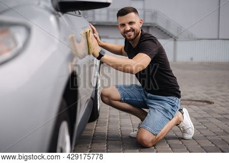 Handsome Man Wipes A Car With A Rag In A Showroom At A Self-service Car Wash. Gray Car
