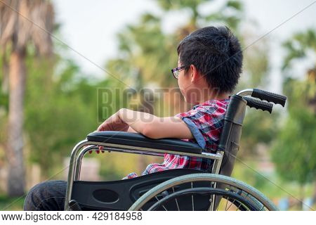 In The Park, A Child In A Wheelchair. Take A Closer Look At His Steering Wheel. Medical Concept That