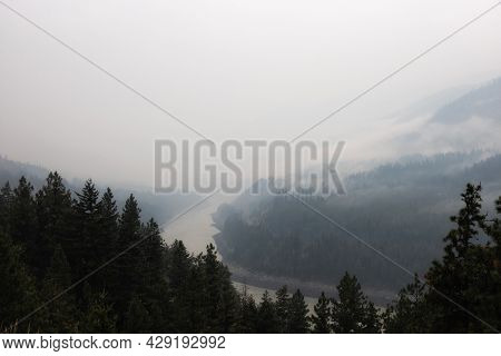 Trees On The Side Of A Mountain In A Valley Covered By Smoke From Forest Wildfire. Nature Disaster. 