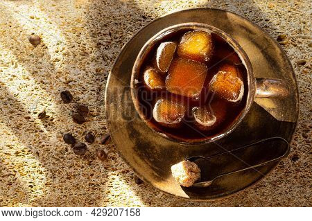 Cubes Of Frozen Coffee In A Ceramic Cup, Next To A Cane Sugar Cube In Tongs On A Saucer And Coffee B