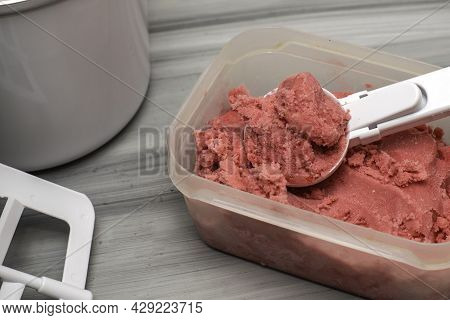 Homemade Cherry Ice Cream In A Plastic Container On The Table With An Ice Cream Spoon And An Ice Cre