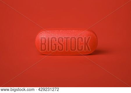 Close up of a single pill tablet in red. Concept for single dose drug, prescription, or medical cure. Blank copy space on pill.