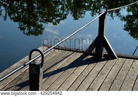 A Wooden Raft Is Tied To A Taut Rope. Self-service Ferry Across The River, Pond. People Get On And P
