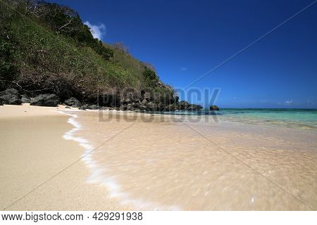 A Sandy Beach Next To A Body Of Water In Fiji