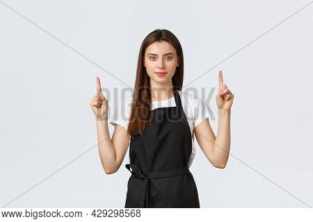 Small Business, Employees And Coffee Shop Concept. Confient Pretty Barista In Black Apron Pointing F
