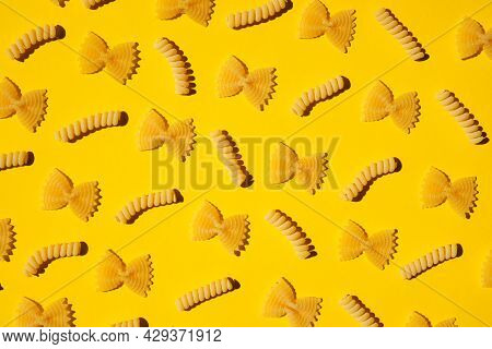 Uncooked Curly Pasta Pattern On Yellow Background. Traditional Dry Raw Macaroni Pattern. Nobody