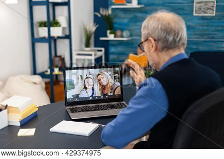 Old Parent Greenting Daughter During Video Conference On Portable Computer. Happy Grandfather Saying