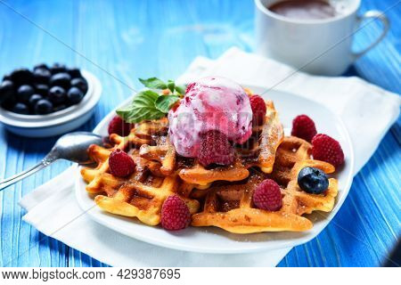 Belgian waffles with fresh berries and ice cream over wooden background. Close up.