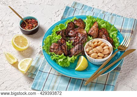 Chicken Liver Fry, Kaleji Fry, Served On Lettuce Leaves With Butter Beans And Lemon Wedges On A Blue