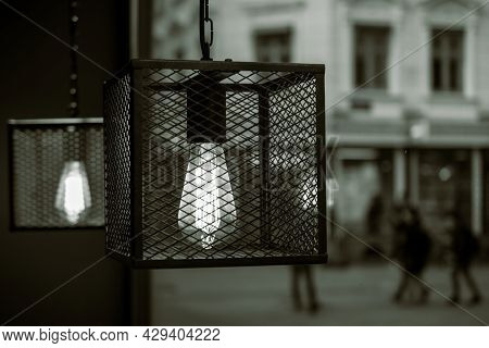 A Black And White Color Of Caged Tungsten Lights By A Window