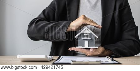 A Small Gray Model House Is An Example Of A Home In A Housing Project, An Insurance Salesperson Is D